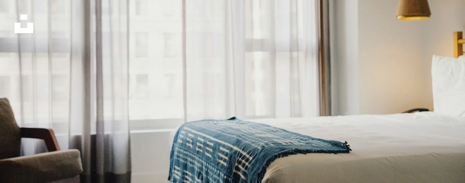 A hotel guest room with a bed, armchair and window