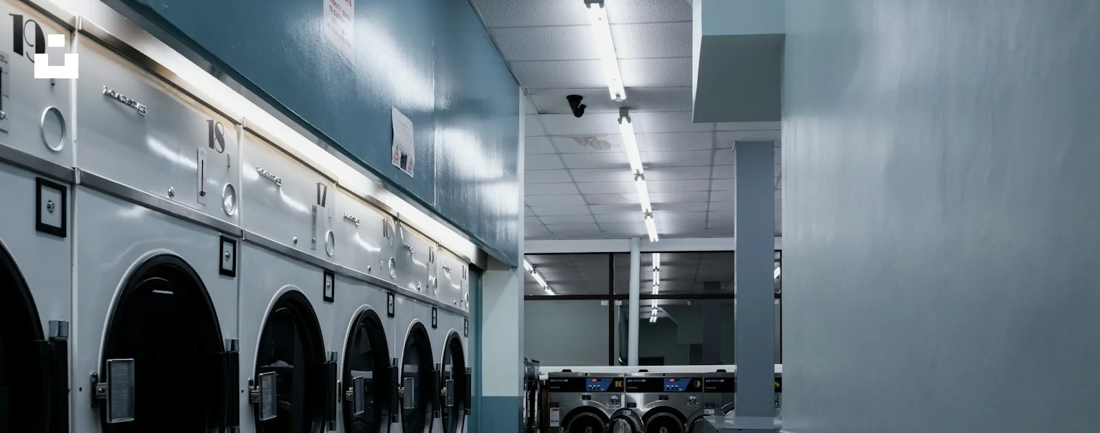 Rows of washing machines and tumble dryers inside a laundromat