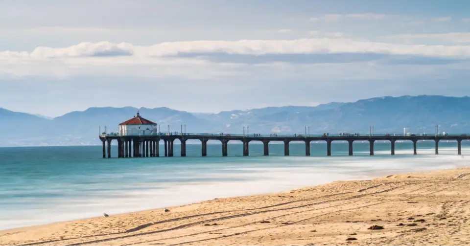Gentle ocean waves beside a sandy beach and pier